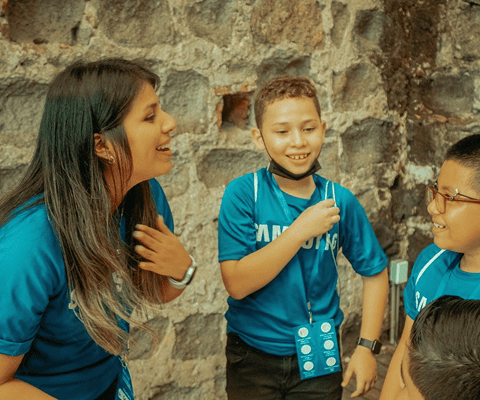 A Samsung employee is happily conversing and laughing with boys during a volunteering activity.