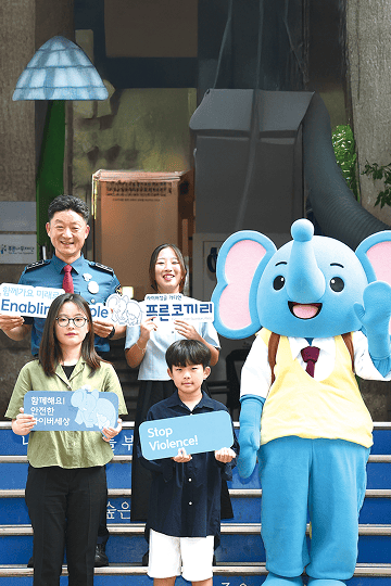 Children with a smile on their face and Blue Elephant mascot waving its hand