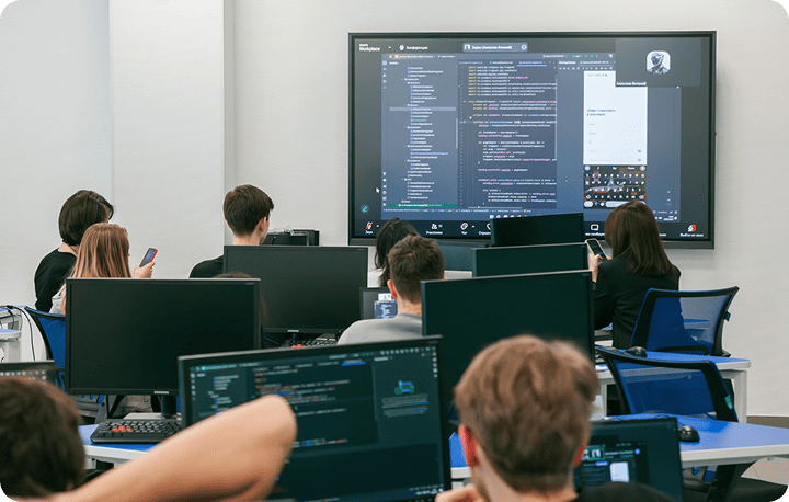 In a class of Samsung Innovation Campus in Russia, trainees are discussing together while looking at coding displayed on the screen.