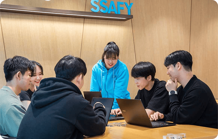 SSAFY trainess gathered together and having a discussion while looking at their laptops