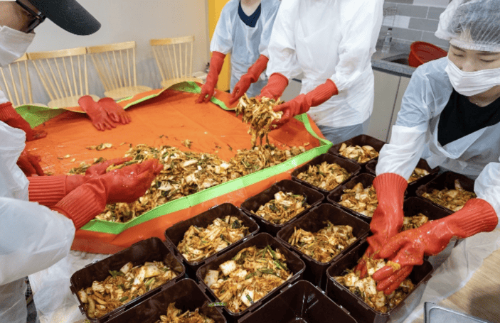 Samsung employees are visiting a community welfare center to prepare kimchi lunchboxes for the elderly.